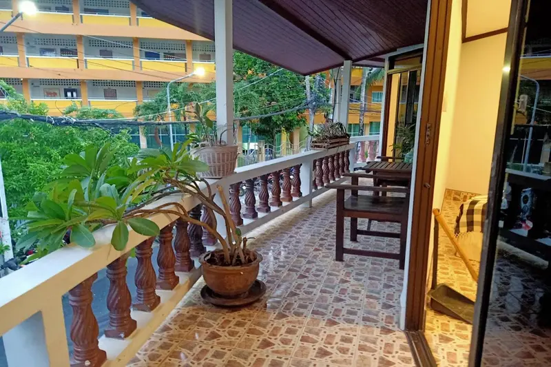 Terrasse carrelée avec mobilier en bois et plantes en pot.