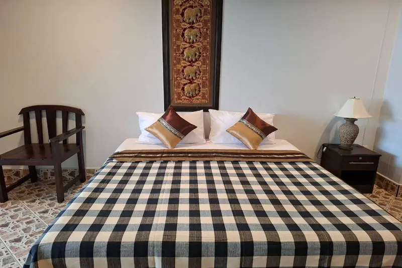 Une chambre avec un lit recouvert d'une couverture à carreaux et une décoration murale.