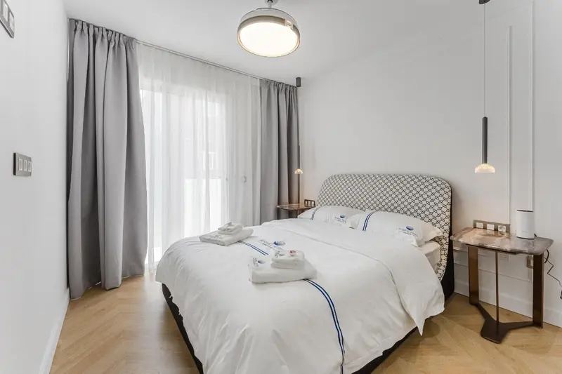 Une chambre lumineuse avec un grand lit couvert de draps blancs.