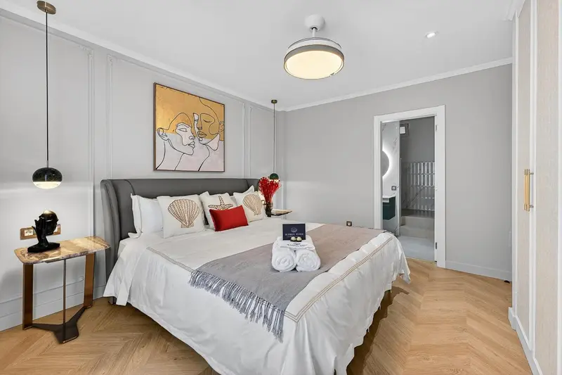 Une chambre lumineuse avec un grand lit recouvert d'une courtepointe et de coussins décoratifs.