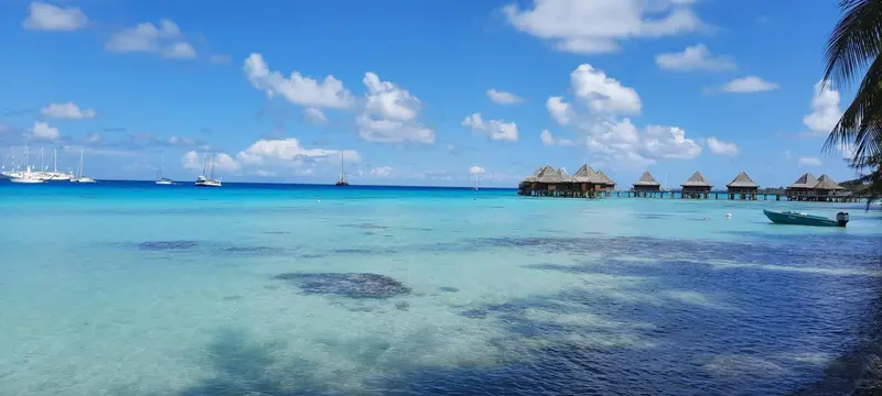 Cabanes sur pilotis au milieu d'une eau turquoise sous un ciel nuageux.