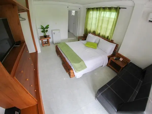 Une chambre lumineuse avec un lit double et un coin salon.