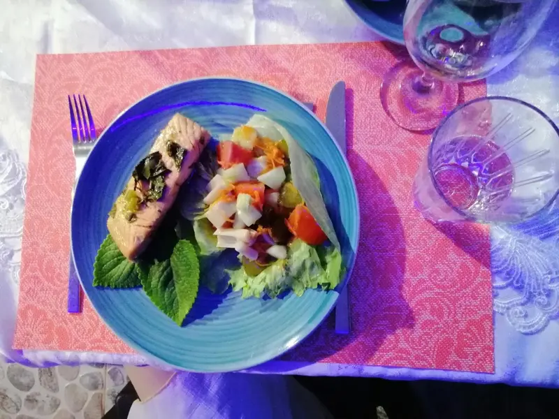 Assiette de poisson servi avec une salade colorée et des verres.