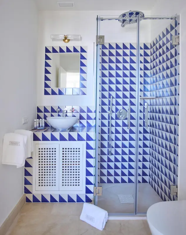 Une salle de bain lumineuse avec une douche à l'italienne aux motifs géométriques.