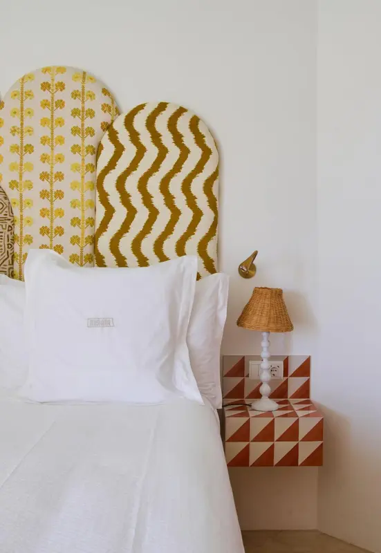 Un lit blanc avec des oreillers moelleux se trouve devant une tête de lit décorative.