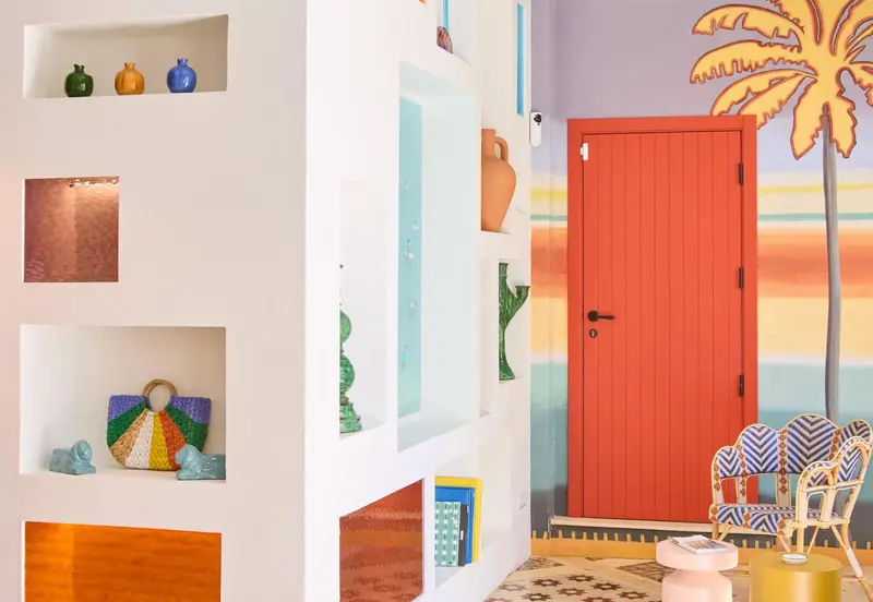 Intérieur coloré avec des niches décoratives et une porte orange.
