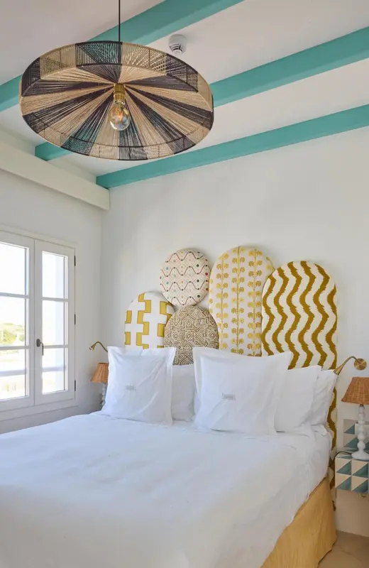 Une chambre lumineuse avec un lit recouvert de linge blanc et une tête de lit décorée.