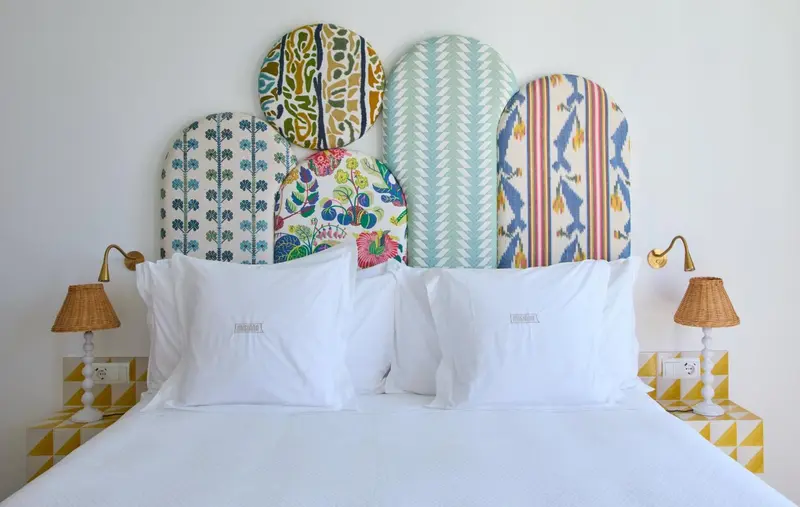 Un lit blanc avec des oreillers moelleux est mis en valeur par une tête de lit décorative colorée.