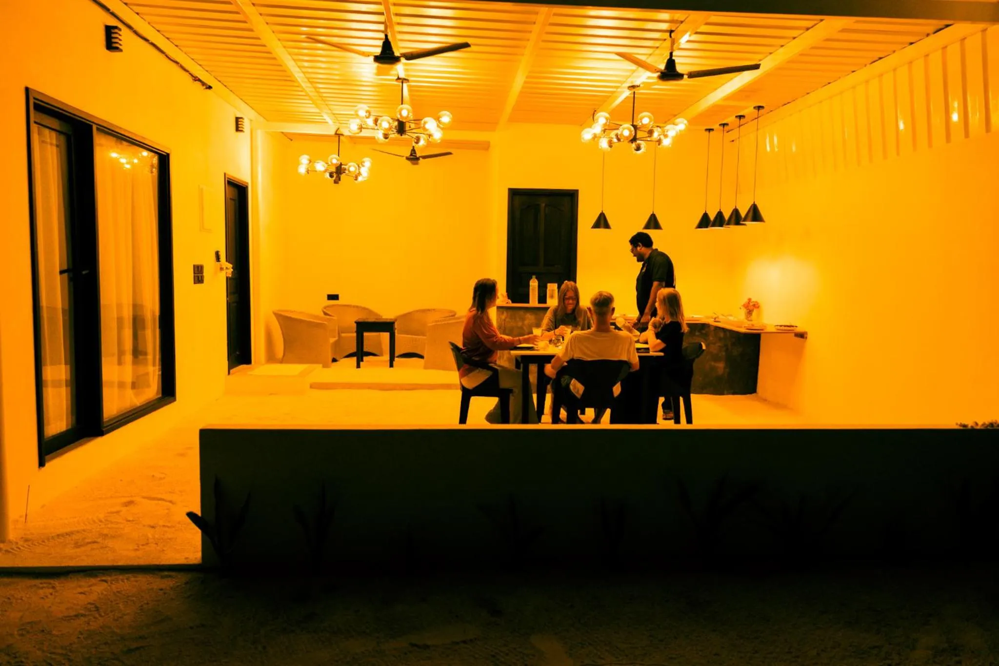 Des convives sont assis autour d'une table dans un espace lumineux et ouvert.