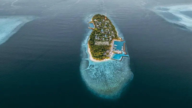 Vue aérienne d'une île tropicale entourée d'eaux turquoise et d'un récif corallien.