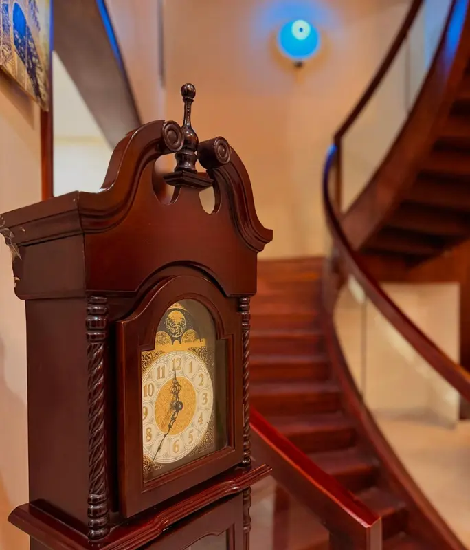 Une horloge ancienne en bois se trouve au pied d'un escalier en colimaçon.