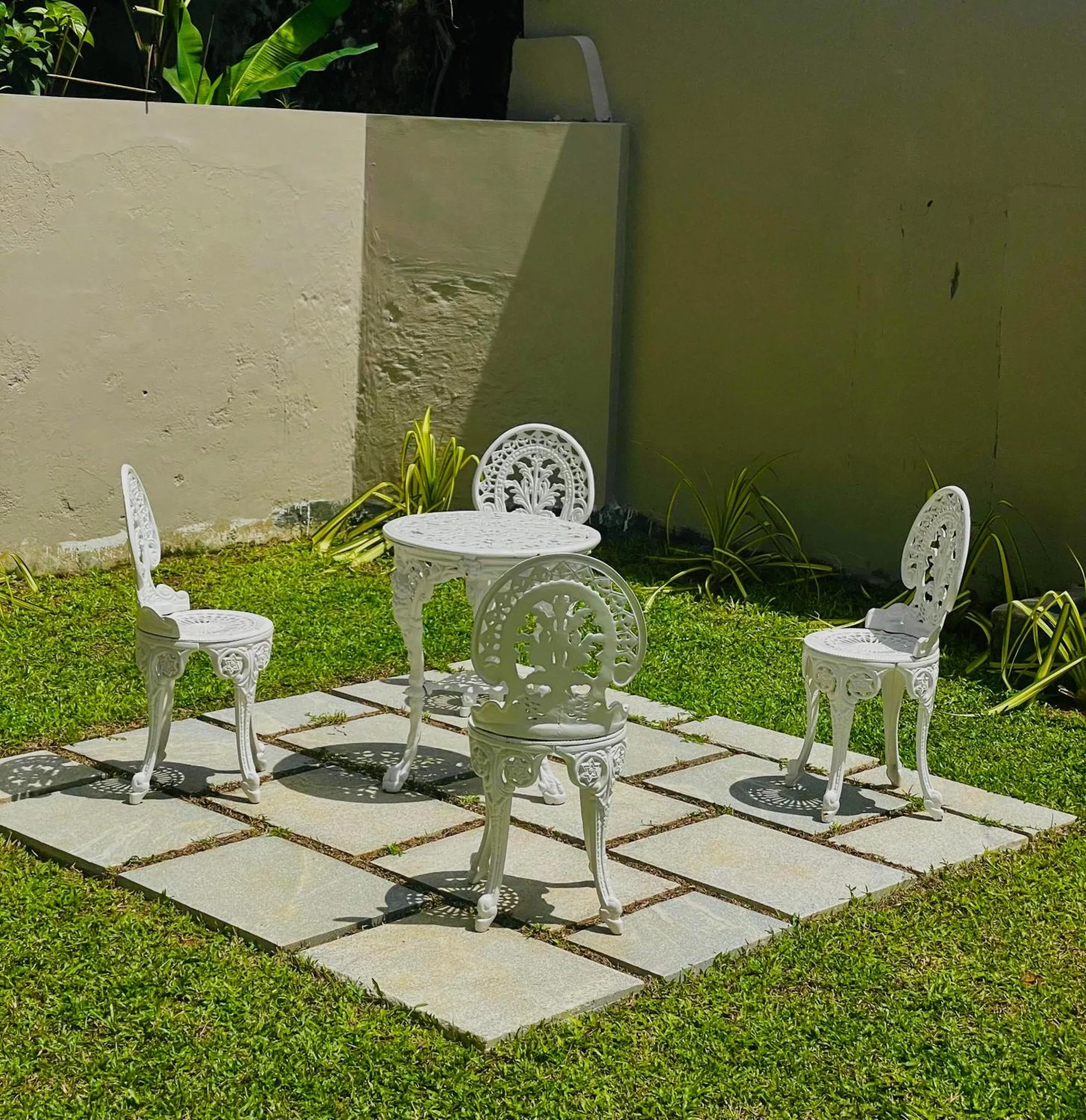 Un ensemble de mobilier blanc en fer forgé est disposé sur une terrasse carrelée.