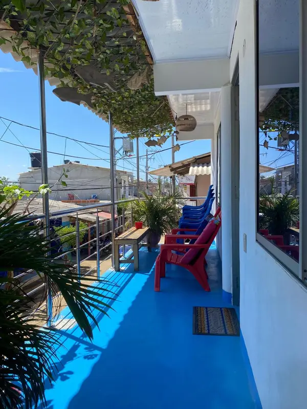 Terrasse ombragée avec mobilier bleu et rouge donnant sur une vue urbaine.