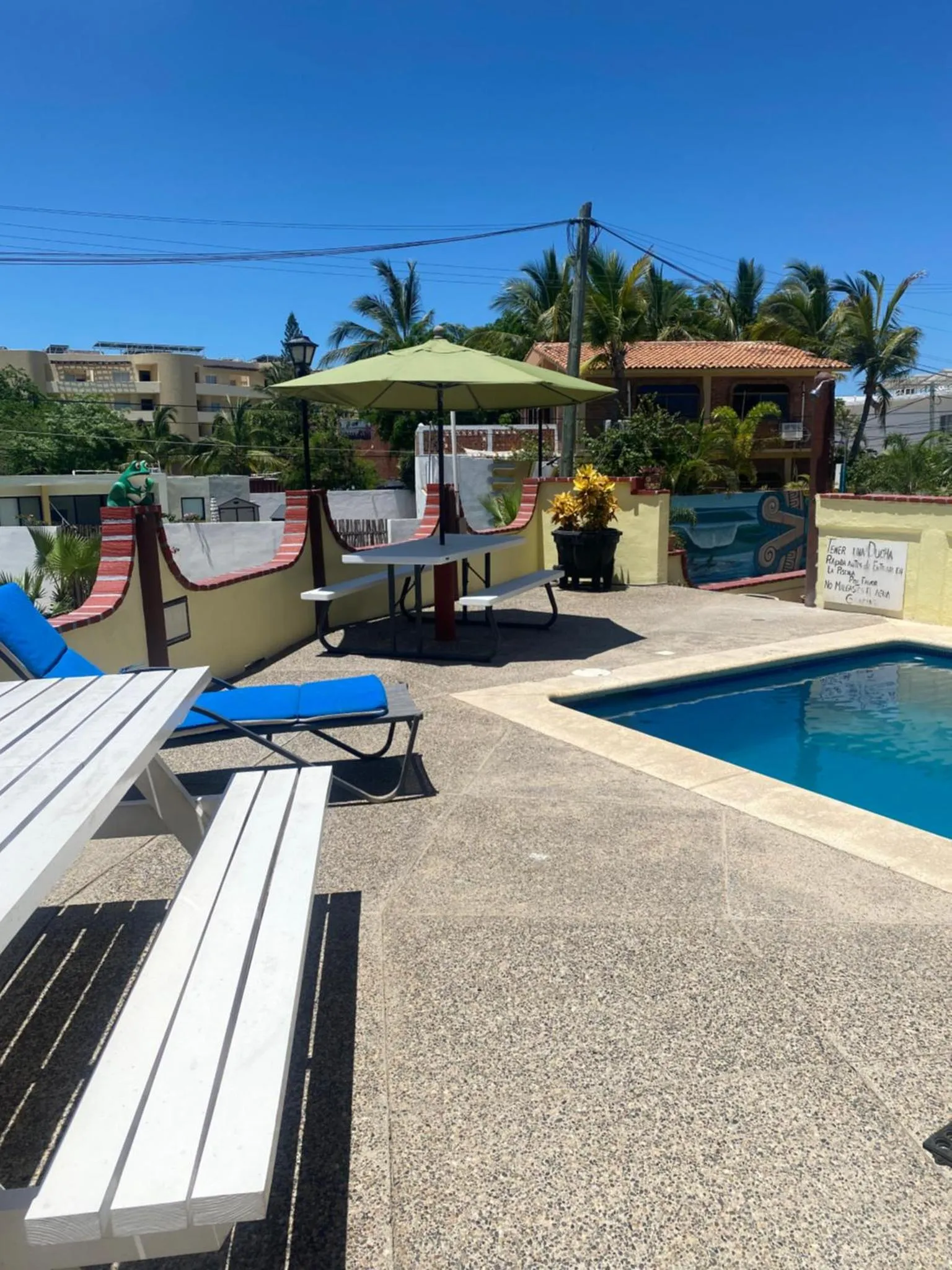Transats blancs disposés autour d'une piscine turquoise sous des parasols verts.
