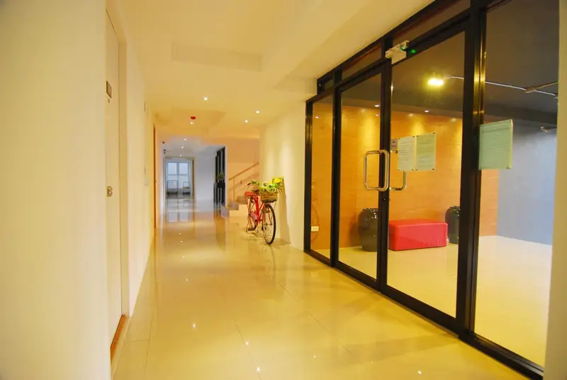 Un couloir d'hôtel mène à une entrée vitrée.