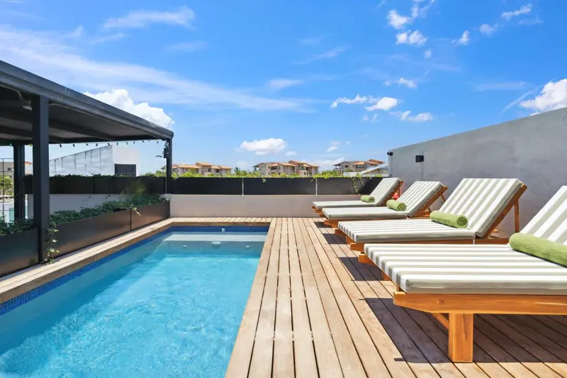 Terrasse avec piscine et chaises longues au soleil.