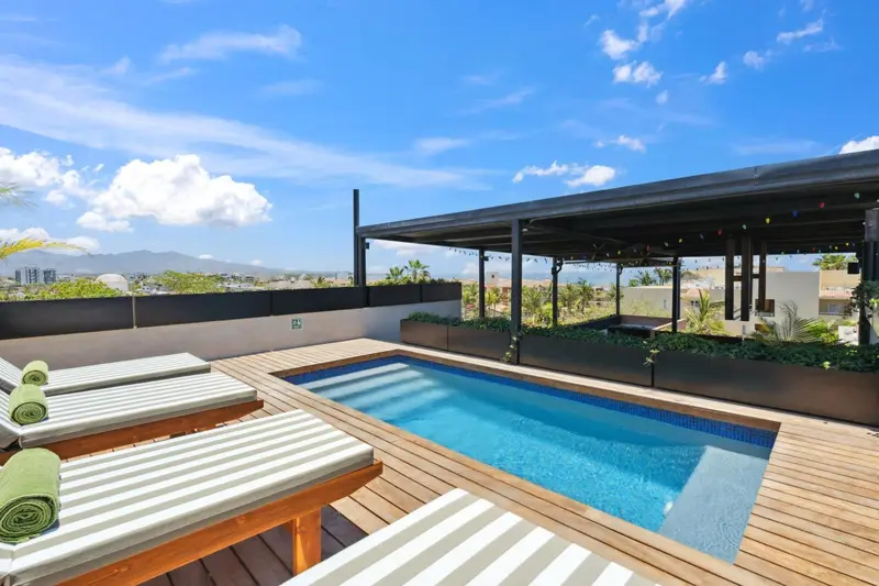 Transats alignés au bord d'une piscine rectangulaire sur une terrasse en bois.