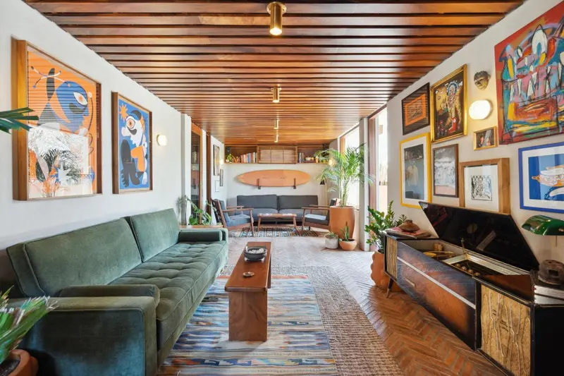 Un espace de détente intérieur avec canapés verts et œuvres d'art colorées.
