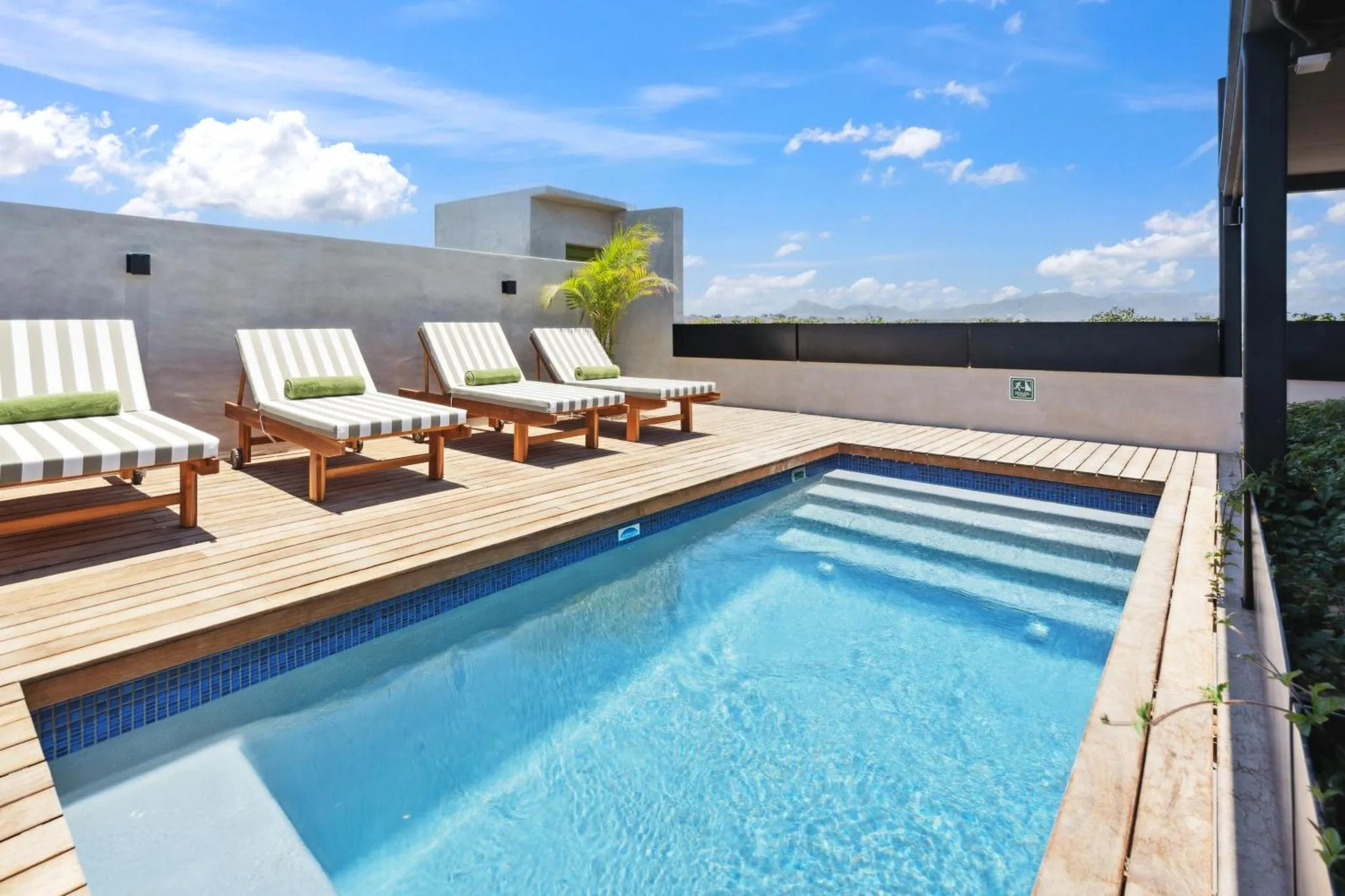 Transats alignés sur une terrasse en bois au bord d'une piscine.