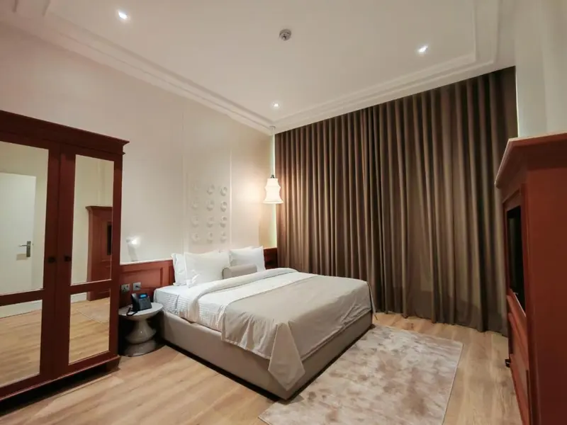 Une chambre lumineuse avec un grand lit et un dressing en bois.