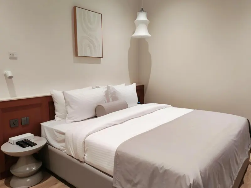 Une chambre lumineuse avec un grand lit recouvert de linge blanc.