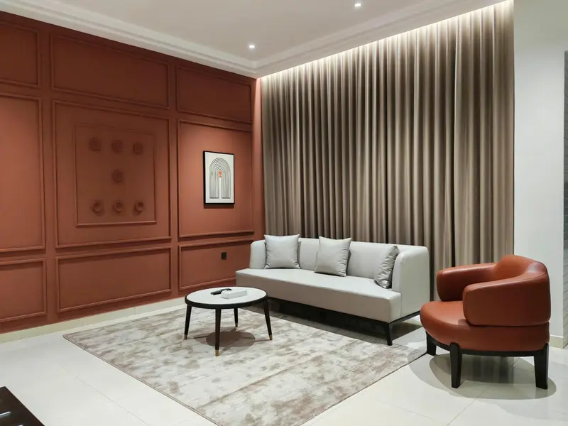 Un salon moderne avec un canapé gris, une table basse et un fauteuil orange.