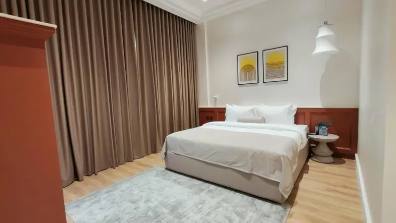 Une chambre lumineuse avec un grand lit et des rideaux beiges.