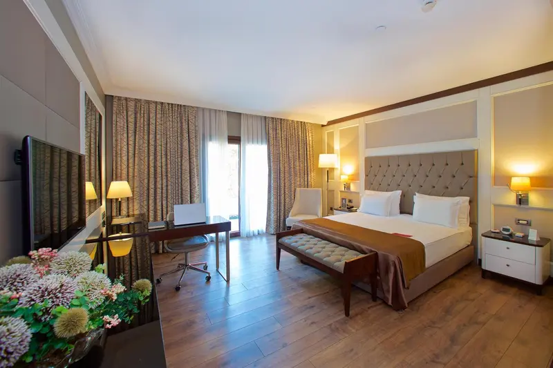 Chambre lumineuse avec un grand lit et un espace bureau.