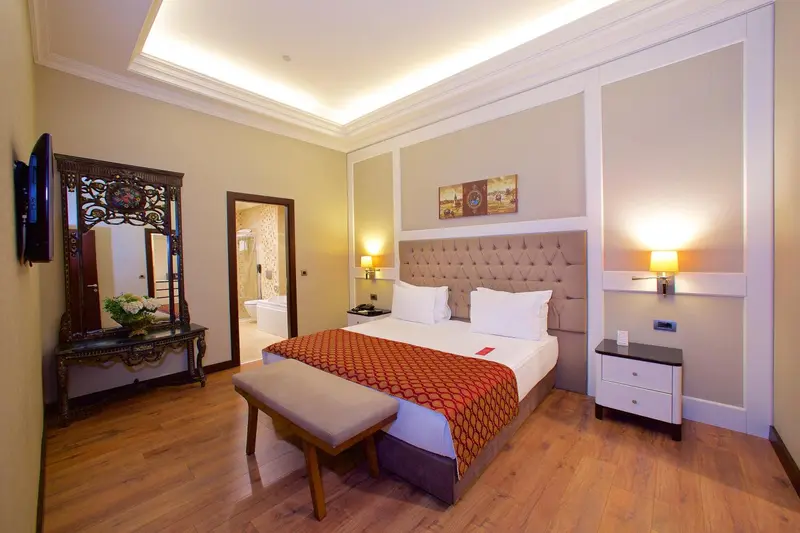 Une chambre lumineuse avec un grand lit et un miroir décoratif.