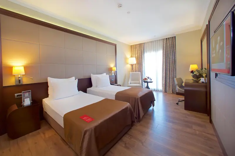 Une chambre lumineuse avec deux lits simples et un coin salon.