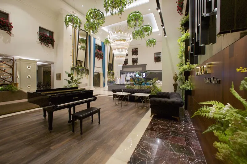 Un hall d'accueil spacieux avec un piano à queue et des plantes suspendues.