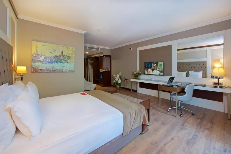 Une chambre lumineuse avec un grand lit et un espace bureau.
