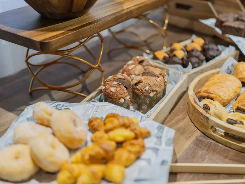 Assortiment de viennoiseries et pâtisseries sur un présentoir en bois.