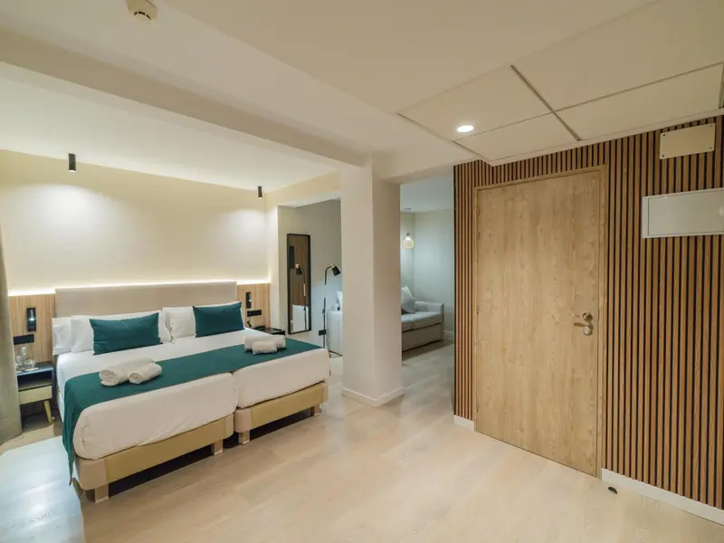 Chambre lumineuse avec un grand lit et un espace détente attenant.