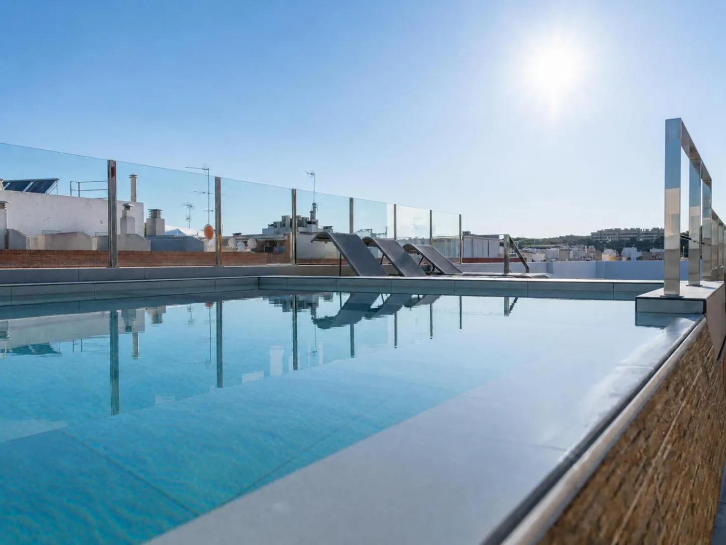 Piscine rectangulaire sur un toit-terrasse ensoleillé avec vue sur la ville.