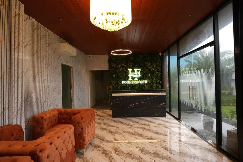 Hall d'accueil lumineux avec un comptoir en marbre et un canapé orange.