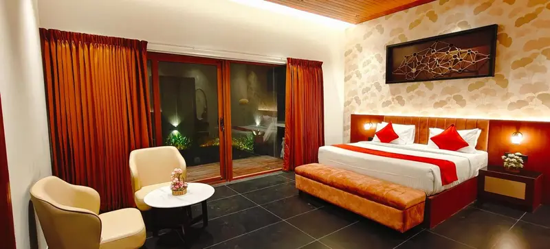 Une chambre lumineuse avec un lit double et un coin salon donnant sur une terrasse.