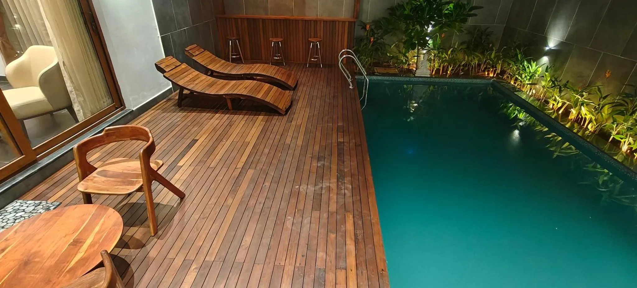 Terrasse en bois avec chaises longues et petite piscine.