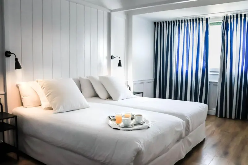 Un lit double est prepare avec des oreillers blancs et une table basse avec des boissons.