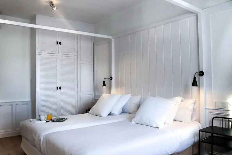 Un lit blanc est dispose dans une chambre claire et minimaliste.