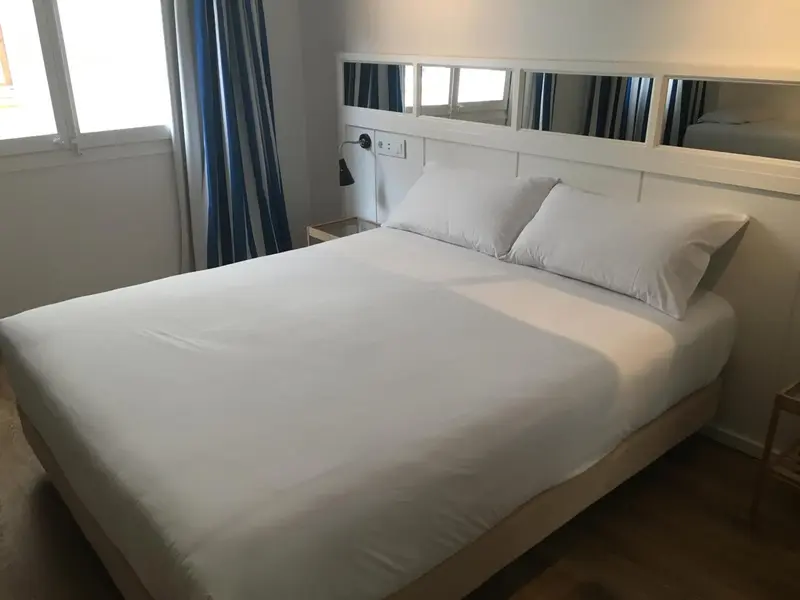 Une chambre lumineuse avec un grand lit recouvert de draps blancs.
