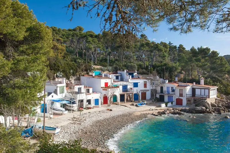 Vue d'un ensemble de bâtiments blancs au bord de mer et d'une plage de galets.