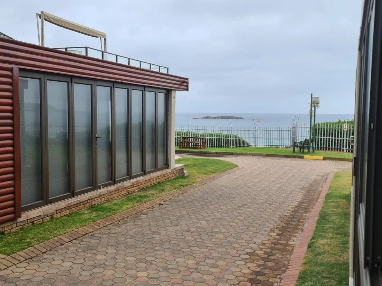 Allée pavée menant à des bâtiments avec vue sur la mer.