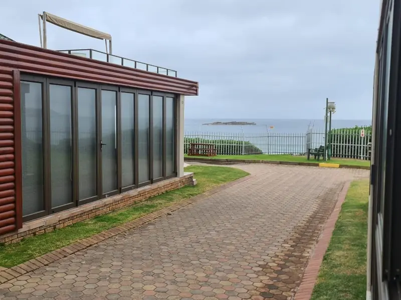 Allée pavée menant à des bâtiments avec vue sur la mer.