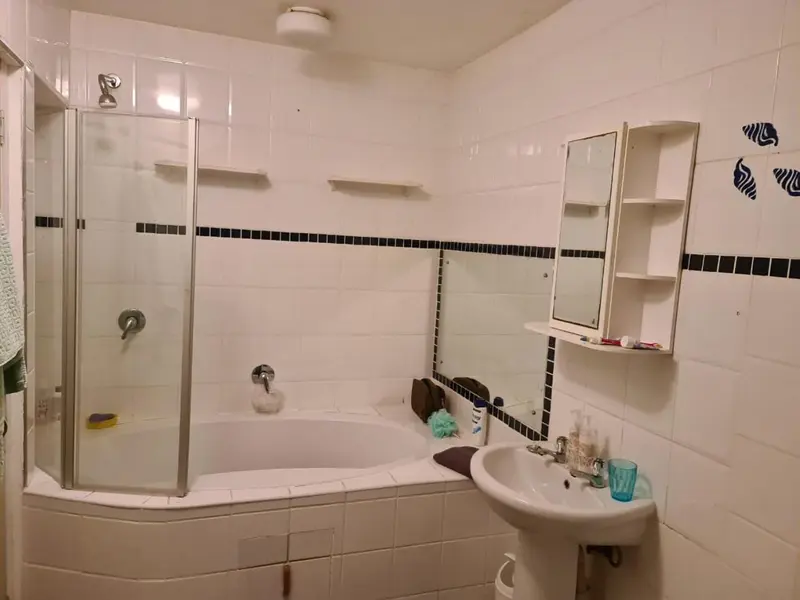 Une salle de bain claire avec baignoire et douche.