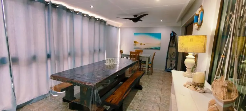 Une longue table en bois est entourée de bancs dans une salle à manger lumineuse.