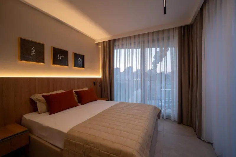 Une chambre lumineuse avec un grand lit et un accès à un balcon.
