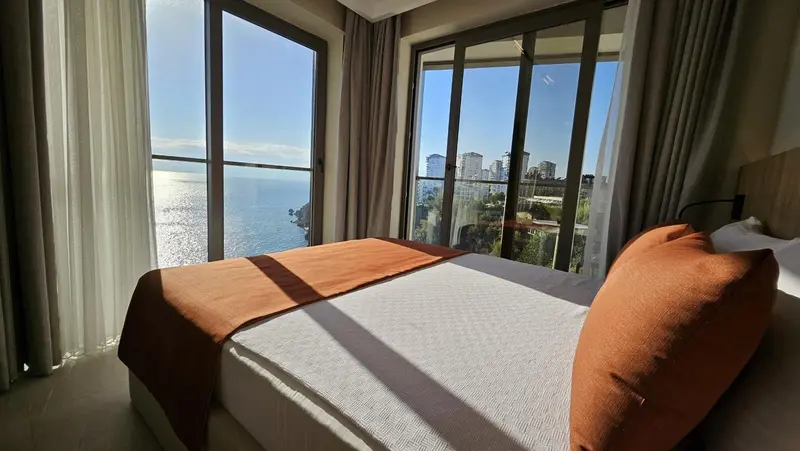 Une chambre lumineuse avec un lit fait donnant sur une vue mer.