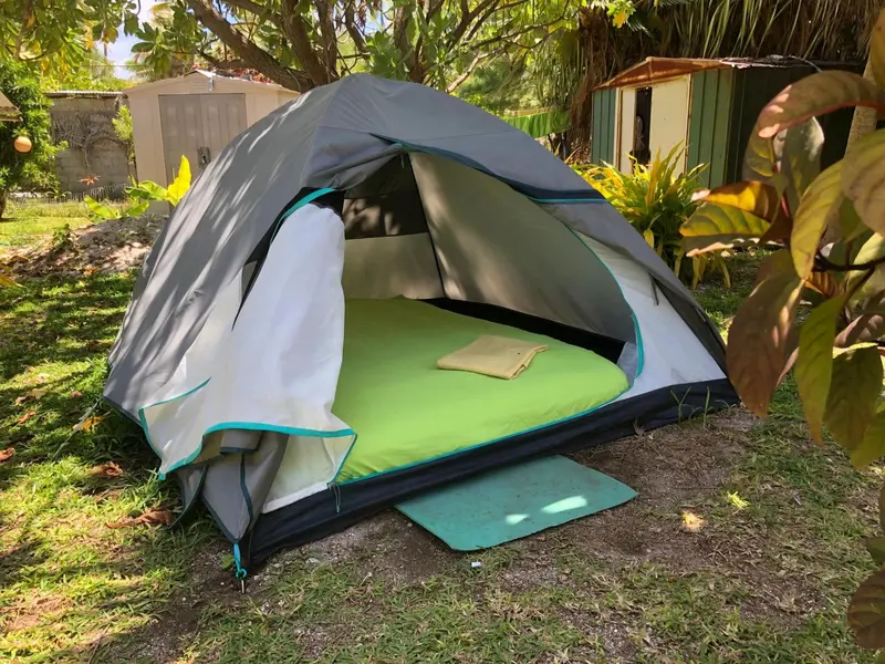 Une tente de camping est installée sur une pelouse verdoyante.