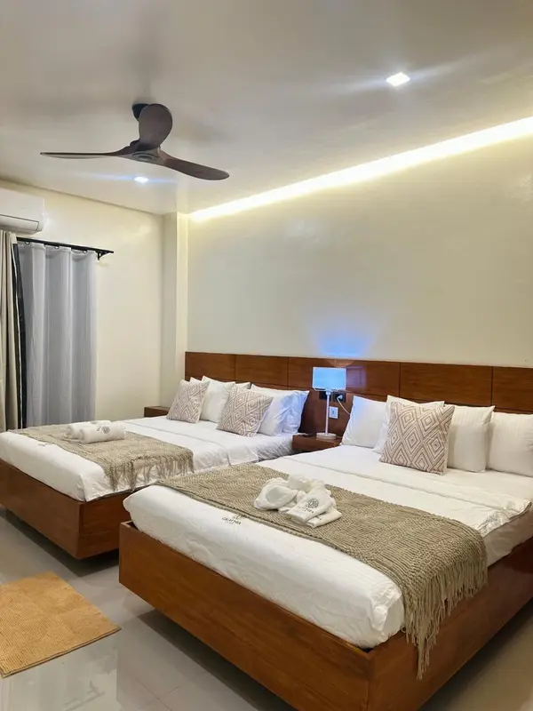 Une chambre lumineuse avec deux lits doubles décorés de coussins et de serviettes.